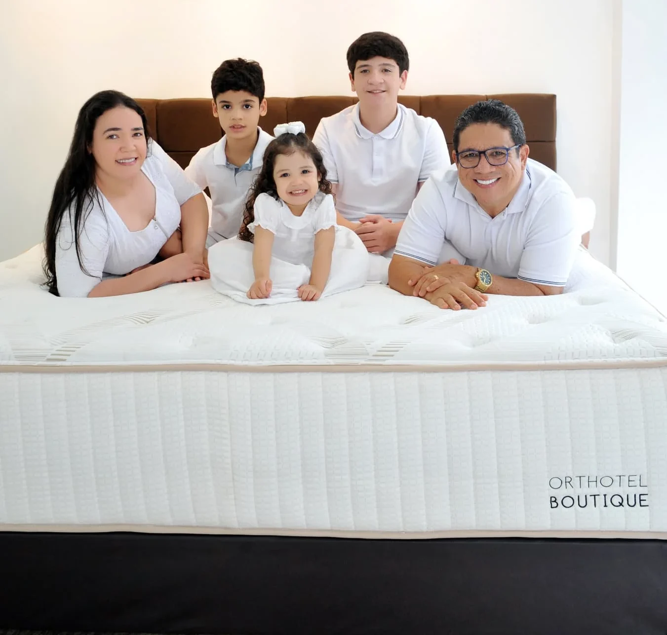 Família reunida sobre o colchão Orthotel Boutique na loja Oficial Colchões & Conforto